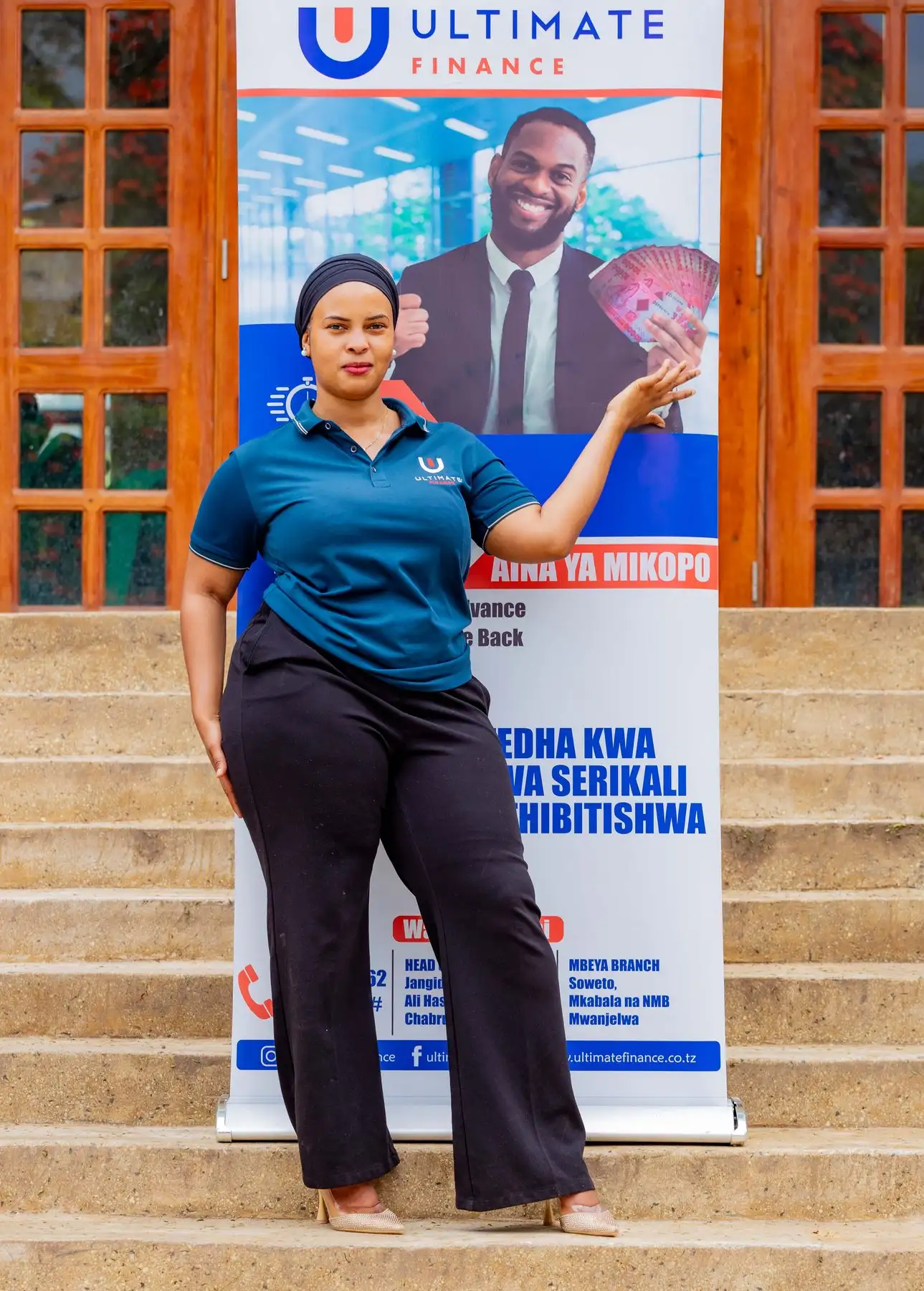 A member of staff in a branded polo shirt standing beside an Ultimate Finance pull-up banner