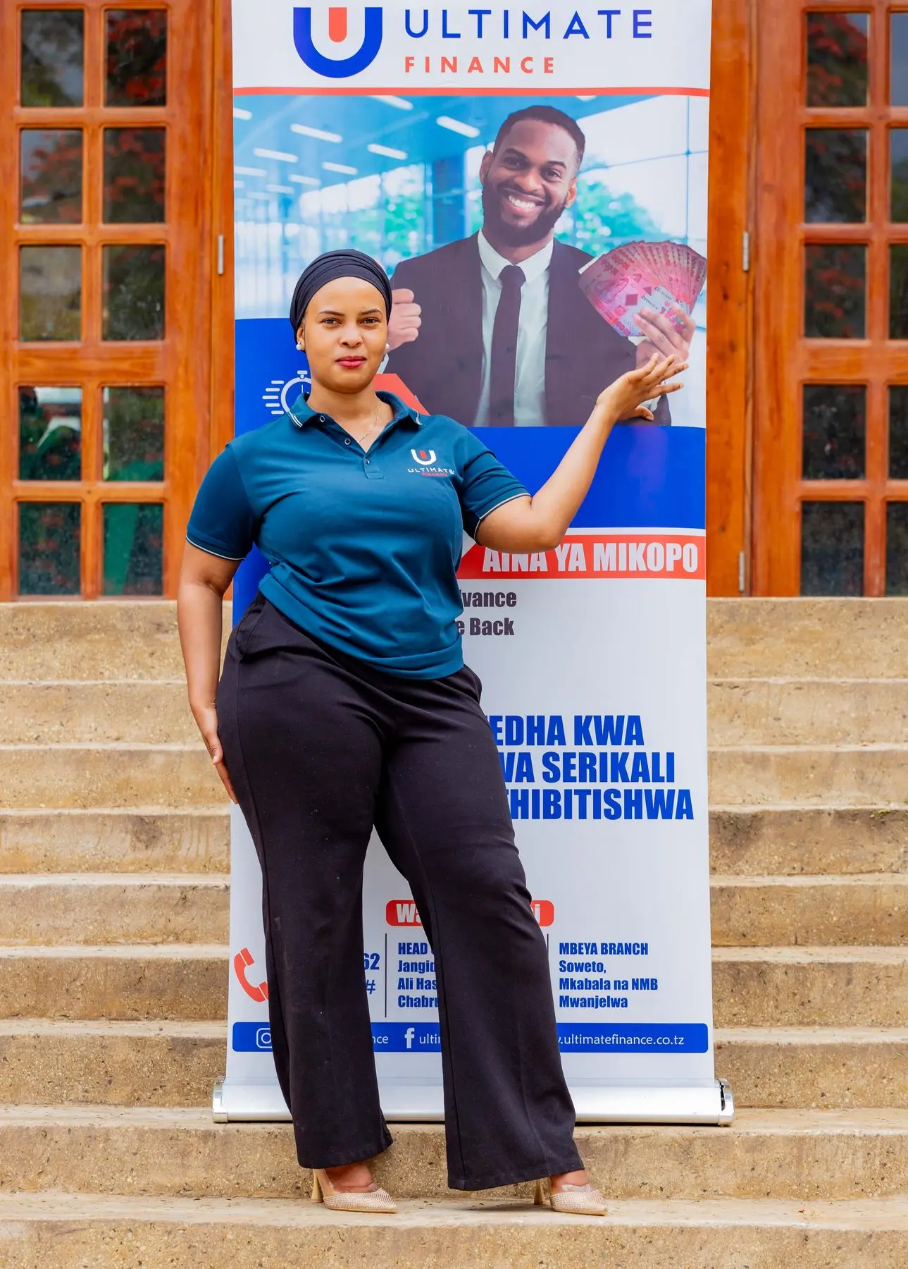 A member of staff in a branded polo shirt standing beside an Ultimate Finance pull-up banner