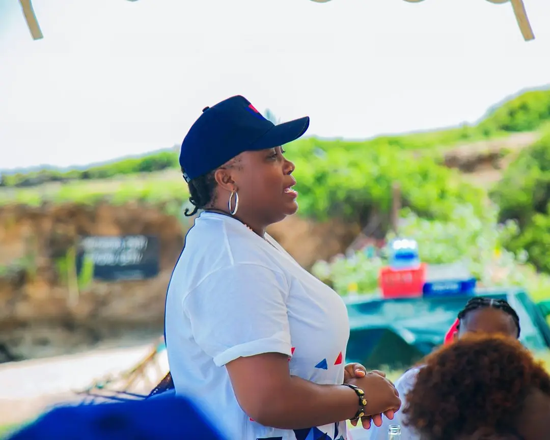 A member of staff in an Ultimate Finance cap speaking with people outdoors at an open-air event