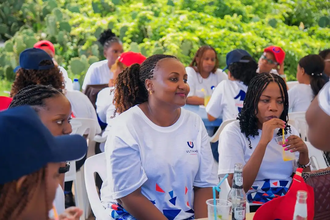 Staff in white branded t-shirts seated outdoors with drinks, several wearing caps