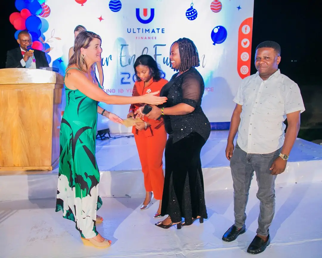 Colleagues on stage receiving recognition beside a lectern and balloon decorations