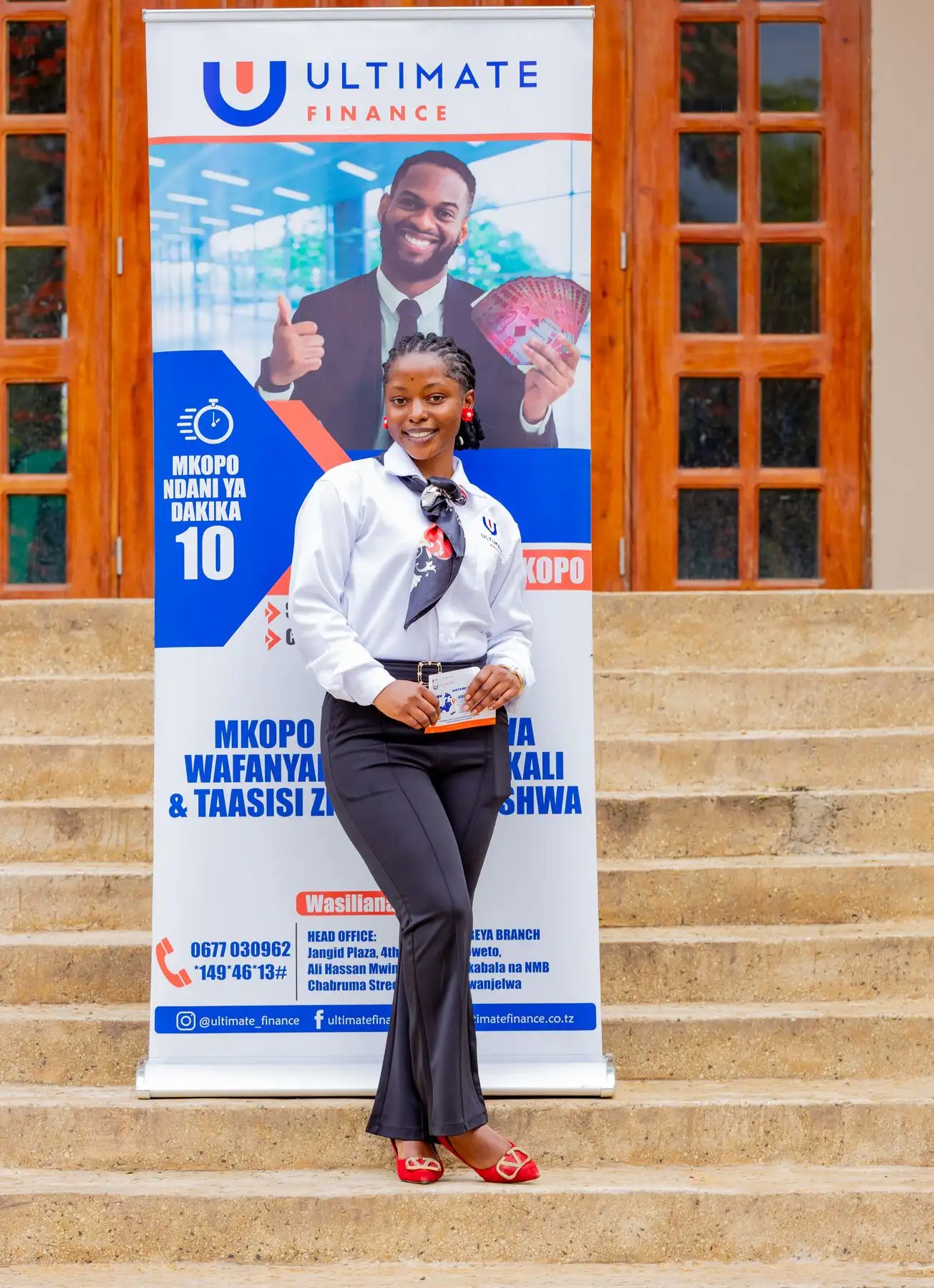 A member of staff in a white shirt standing beside an Ultimate Finance pull-up banner advertising loans within ten minutes