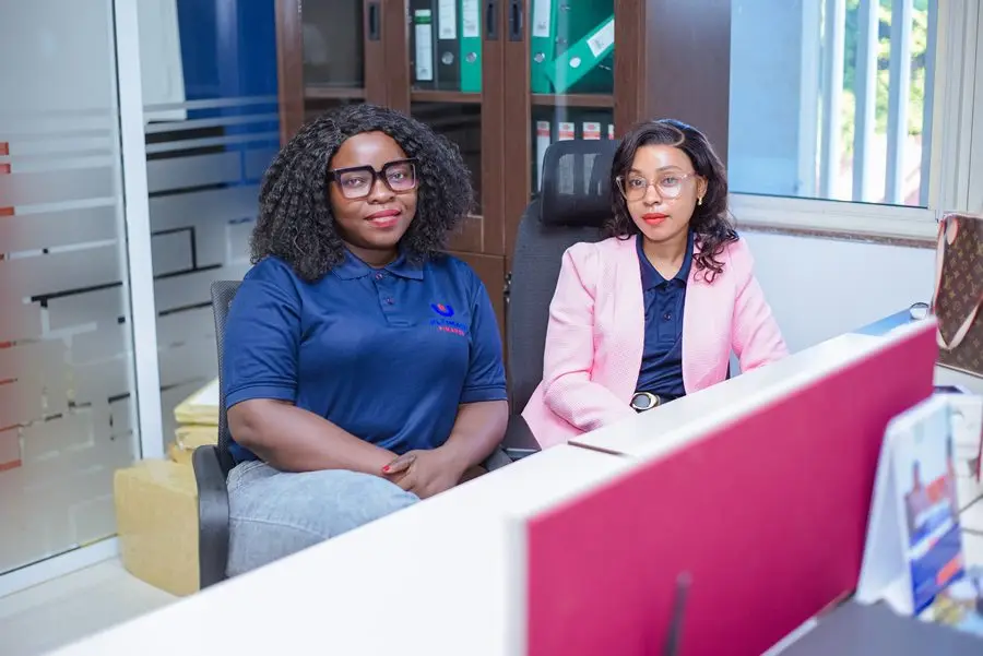 Two members of staff seated together at an office reception desk