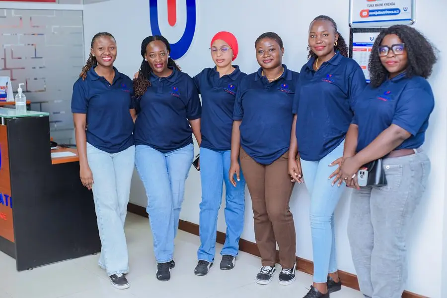 Six members of staff in navy branded polo shirts standing in a row in front of a whiteboard and the Ultimate Finance monogram
