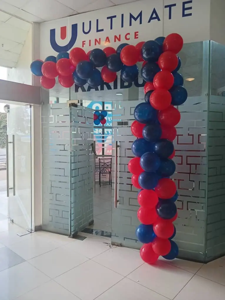 A branch entrance with Ultimate Finance signage above the door and an arch of navy and red balloons beside it