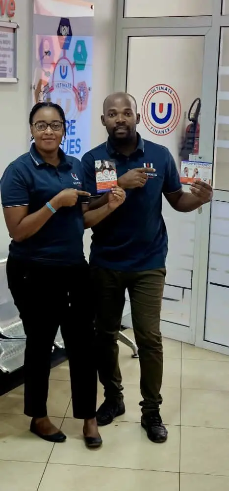 A woman and a man in branded polo shirts standing together in a branch office, holding a leaflet between them