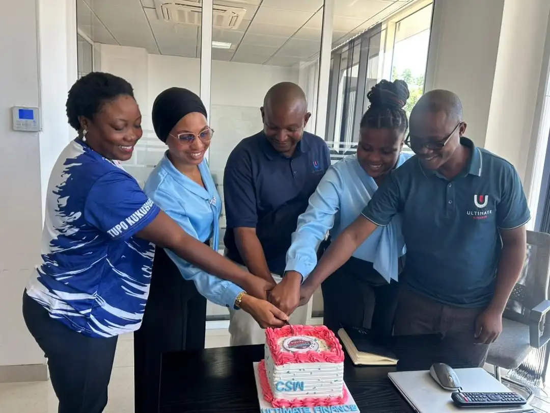 Five colleagues cutting a Customer Service Week cake together at an office desk