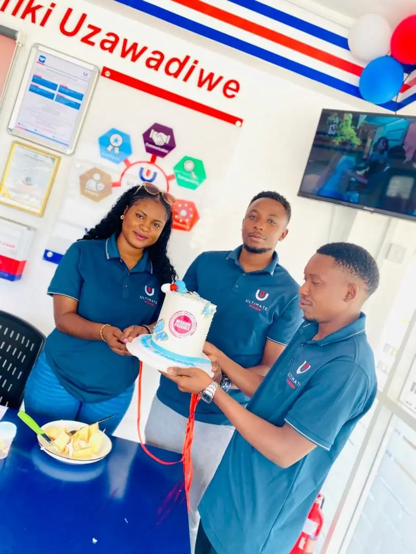 Three members of staff in branded polo shirts holding up a decorated Customer Service Week cake together