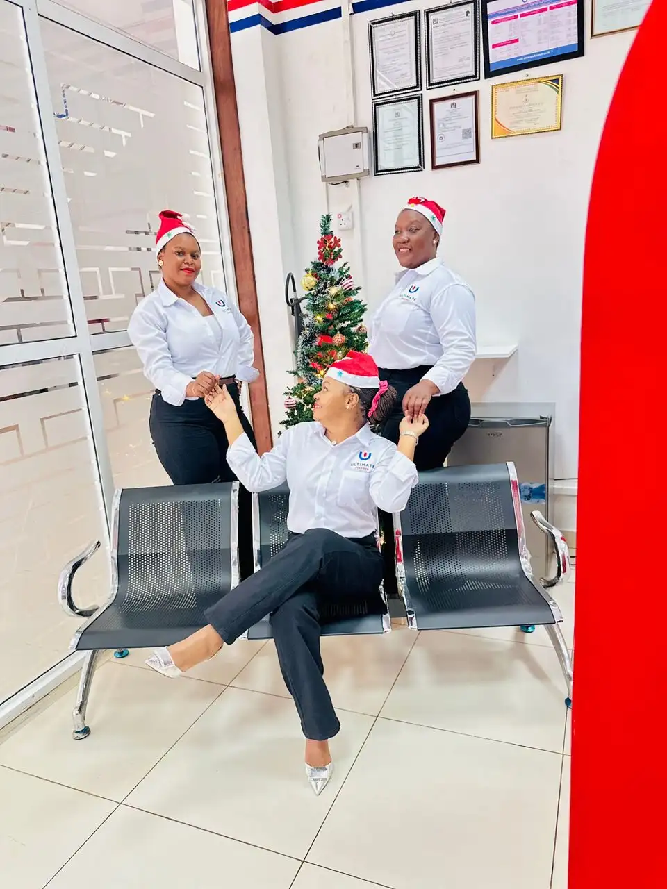 Three members of staff wearing festive hats in a branch waiting area beside a Christmas tree