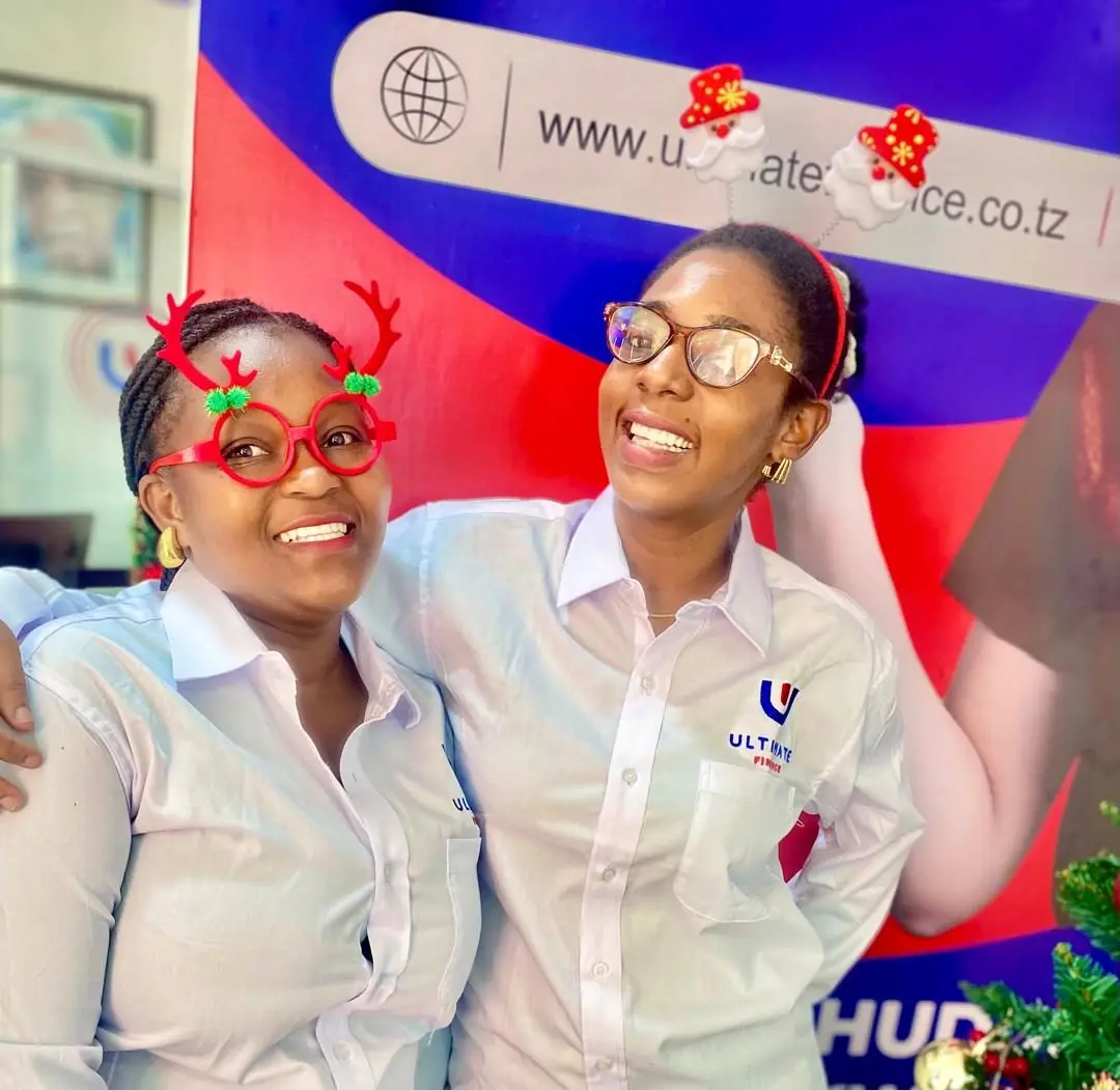 Two members of staff in white branded shirts wearing festive novelty glasses in front of a branded backdrop showing the company website address
